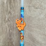 Λευκή στρογγυλή λαμπάδα με μαγνητικό βραχιολάκι με πορτοκαλί δεινοσαυράκι