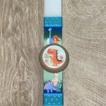 Λευκή πλακέ λαμπάδα με ξύλινο γιογιό με πορτοκαλί δεινοσαυράκι